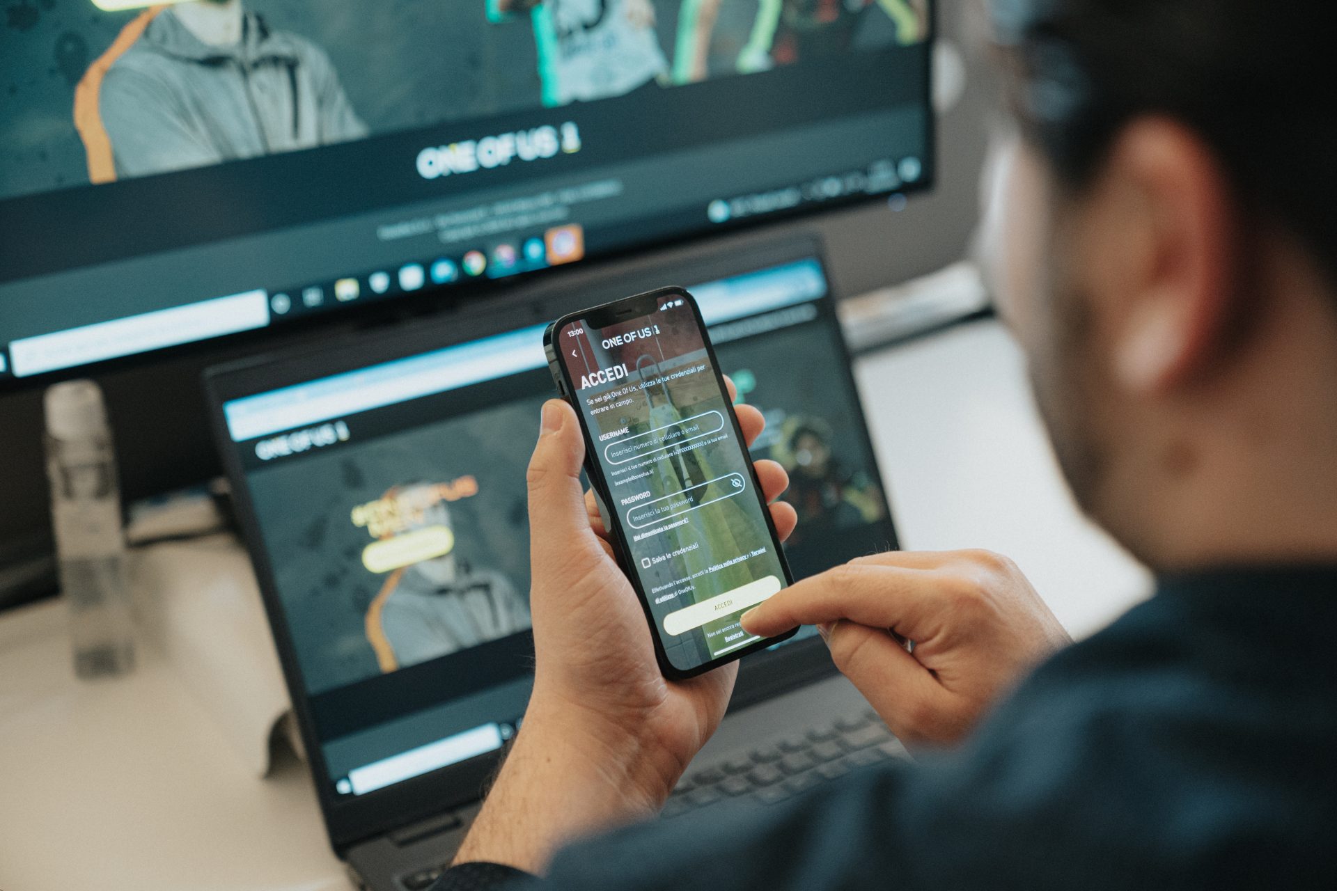 Un ragazzo di spalle con in mano uno smartphone che mostra la schermata dell'app One of Us