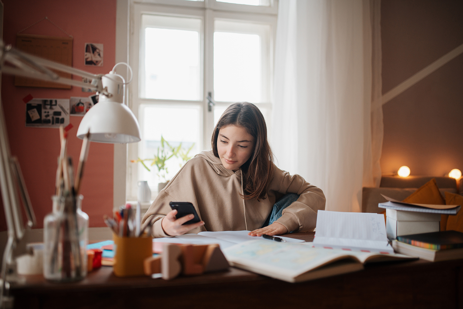 Una ragazza nella sua cameretta che studia matematica con l'aiuto di un'app sul suo smartphone